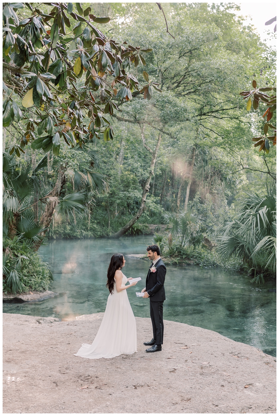 Bride and groom standing on a rock platform exchanging vows at a natural spring during sunrise in Florida.
