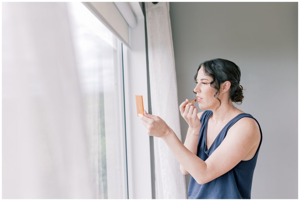 A bride putting on her lipstick at an airbnb while she gets ready for her elopement in Iceland.