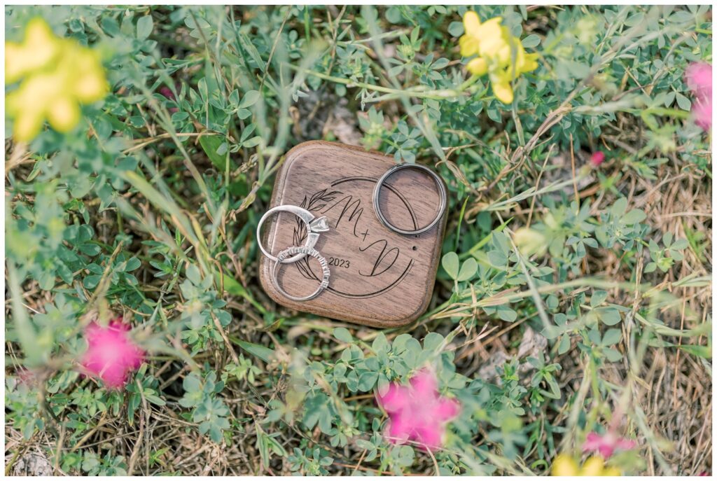 Wedding rings and a custom ring box placed in the grass during an adventure elopement near Lake Placid.
