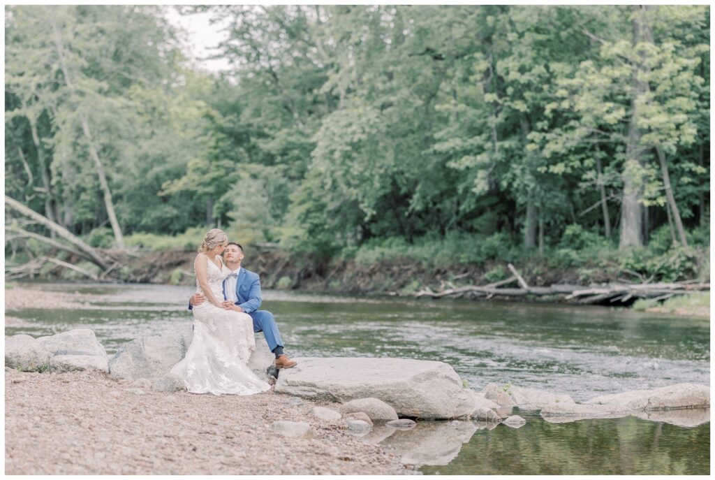 Bride and Groom sitting together on their elopement day near a babbling brook in Keene Valley, NY.
