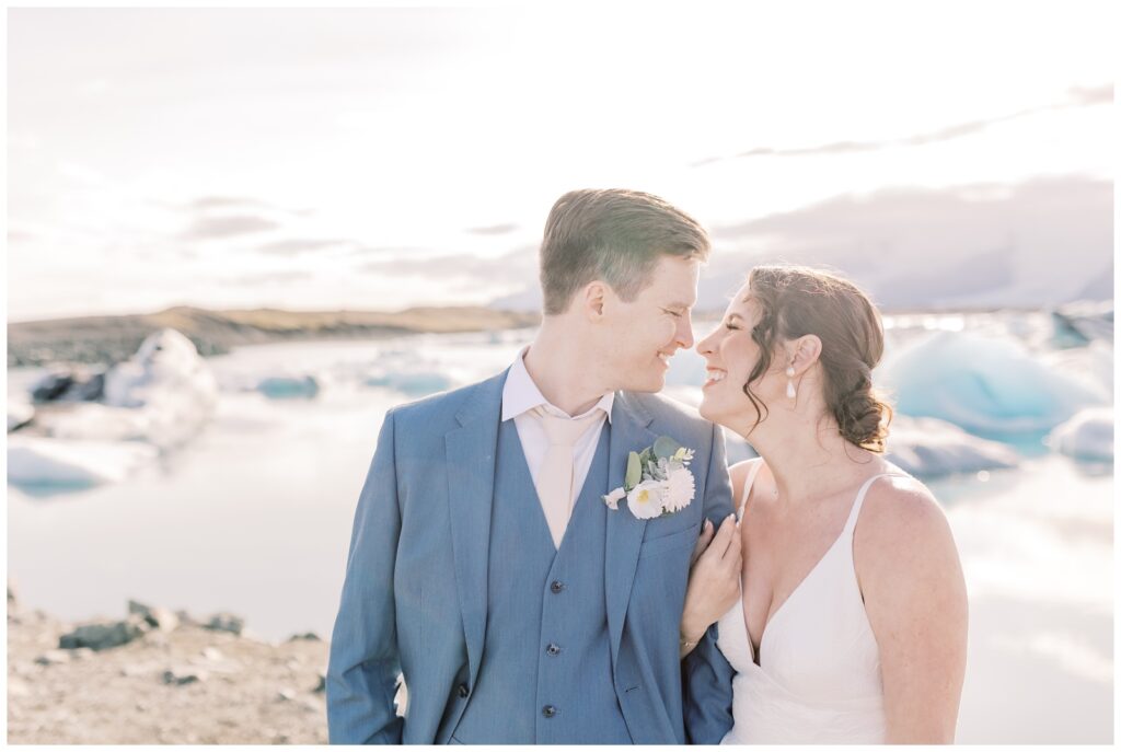 Wedding couple smiling at each other in front of the glaciers at Glacier Lagoon in Iceland during their adventure elopement.