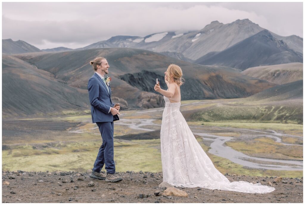 A couple celebrating in the valley of a mountain range after their elopement ceremony in the Highlands of Iceland. 
