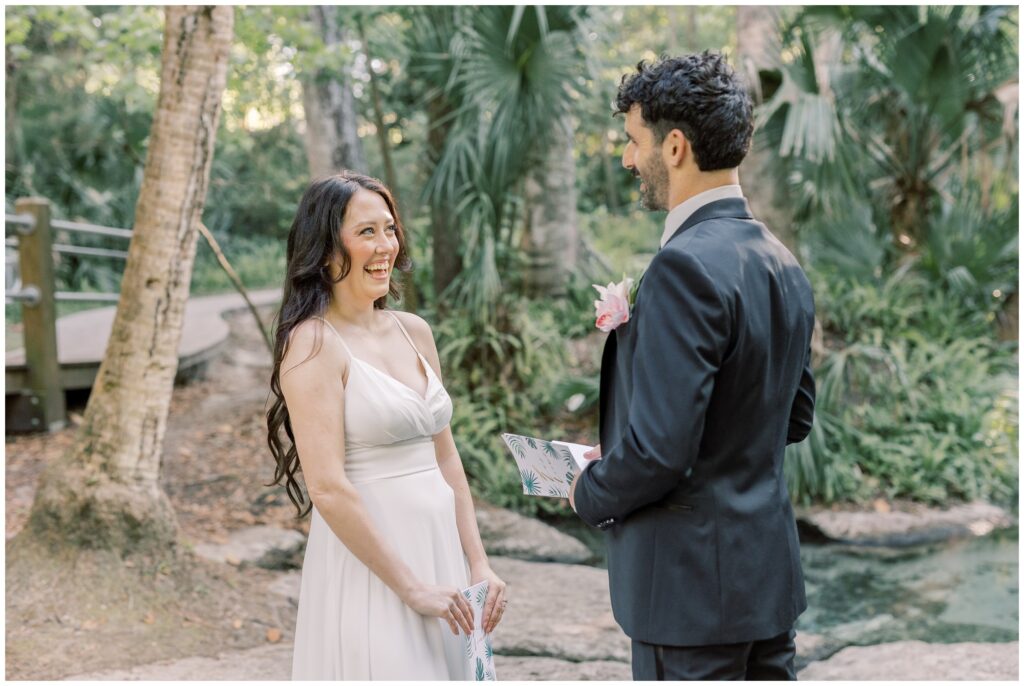 Bride laughing at Groom's vows during intimate ceremony at Kelly Park by a Florida Spring.